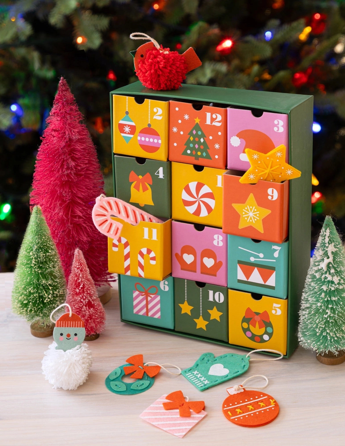 Craft your way to Christmas with the 12 Crafts of Christmas Advent Calendar. Countdown to December 25th with a daily craft surprise! Inside each of the twelve drawers is a fun and easy festive project a child can complete independently, or you can share the experience together.
Every day, a little one can slide open one of the drawers to reveal a felt or pom-pom activity.