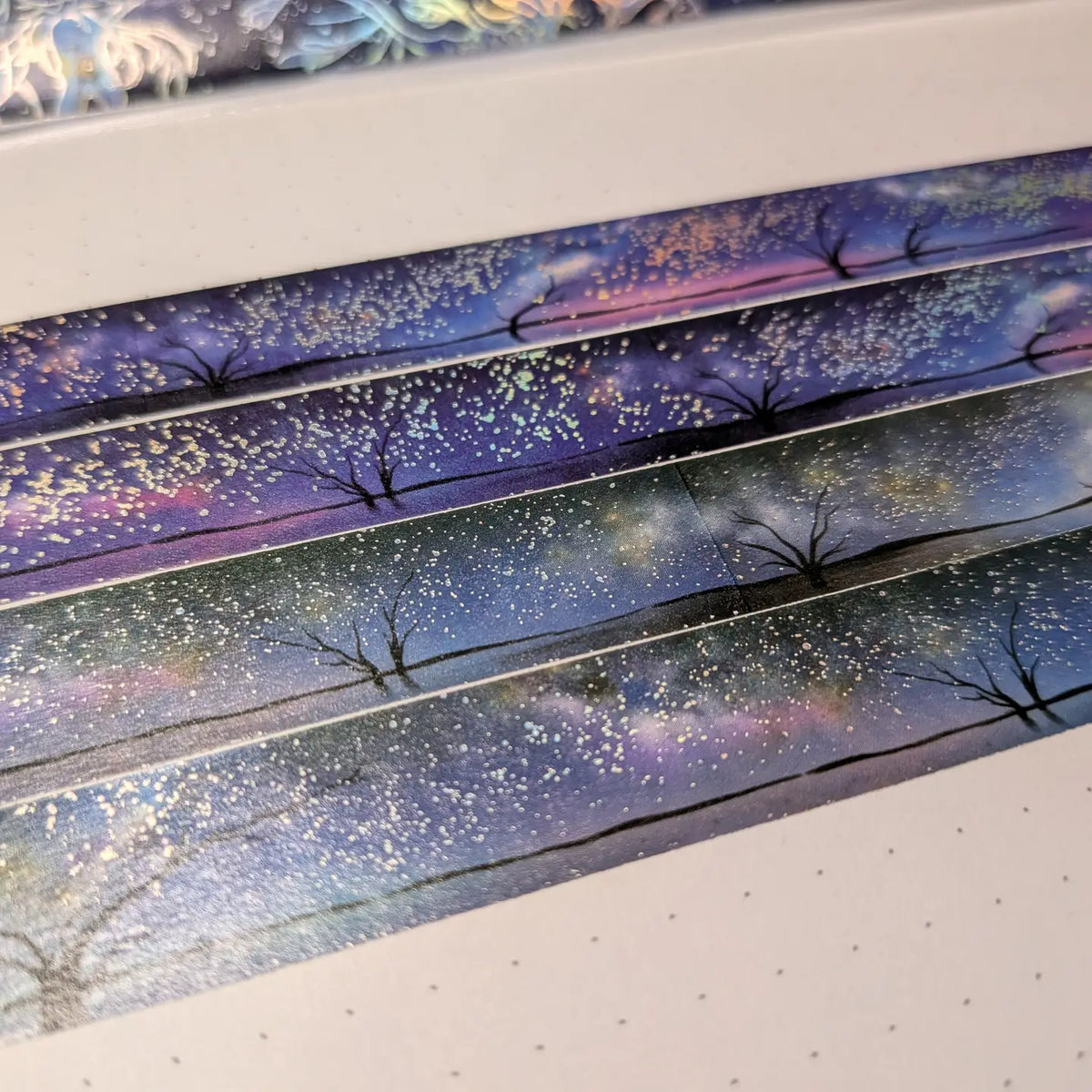 AdrianSlothArt - Holographic Foil Galaxy Washi Tape
Dreamy washi tape with holographic foil stars featuring a landscape with the milky way, tree silhouettes, and water reflections.
Details:
15 mm x 10 m
holographic foil washi tape
There are 2 versions of this design. This listing is for the more saturated version. The second version is more desaturated and has slightly darker colors.