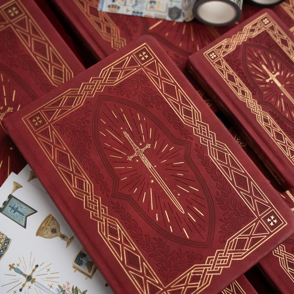 A bold, medieval-inspired notebook designed for adventurers at heart—perfect for journaling, planning, or capturing your next great story. Featuring a rich crimson vegan leather cover with intricate gold-foil detailing and a radiant sword centerpiece, this notebook feels like a treasured tome pulled from a castle library.