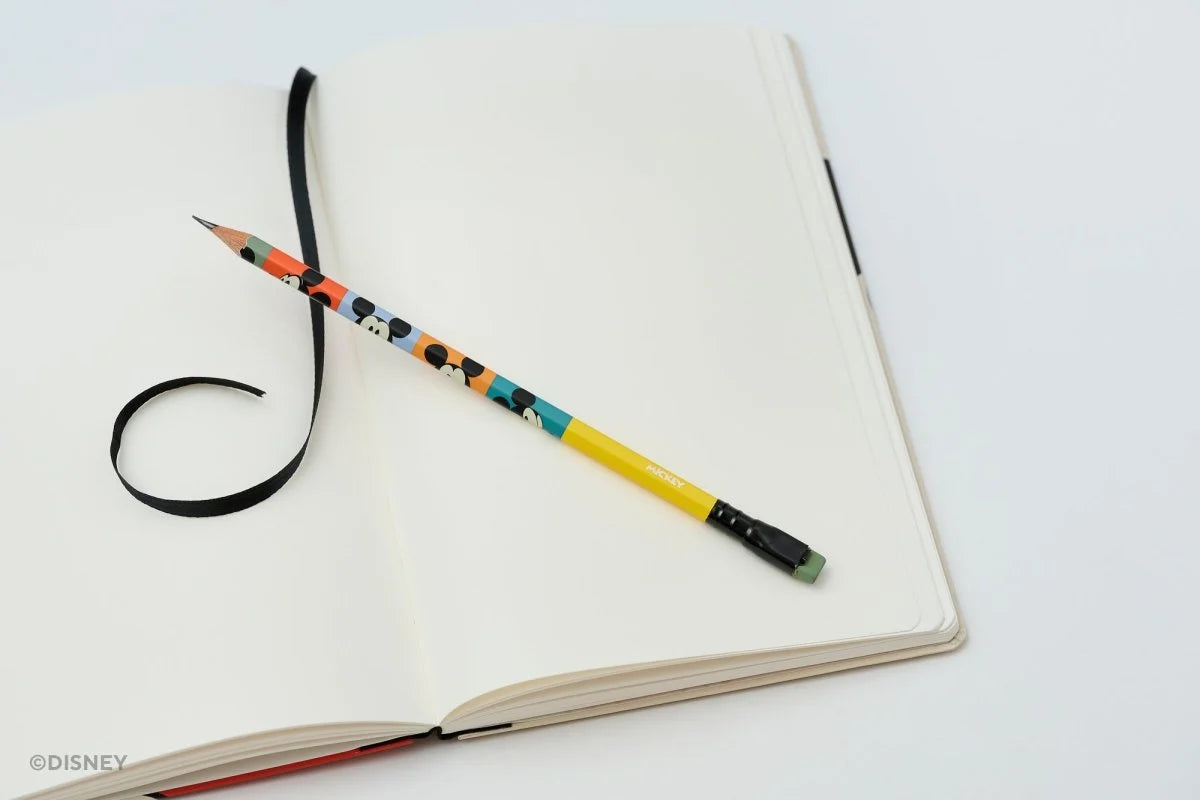 This medium notebook includes 160 pages of 100GSM blank paper and a matte hardcover featuring Mickey and Minnie Mouse. It also has a built-in pencil holster that comes loaded with a Mickey Mouse Blackwing pencil.