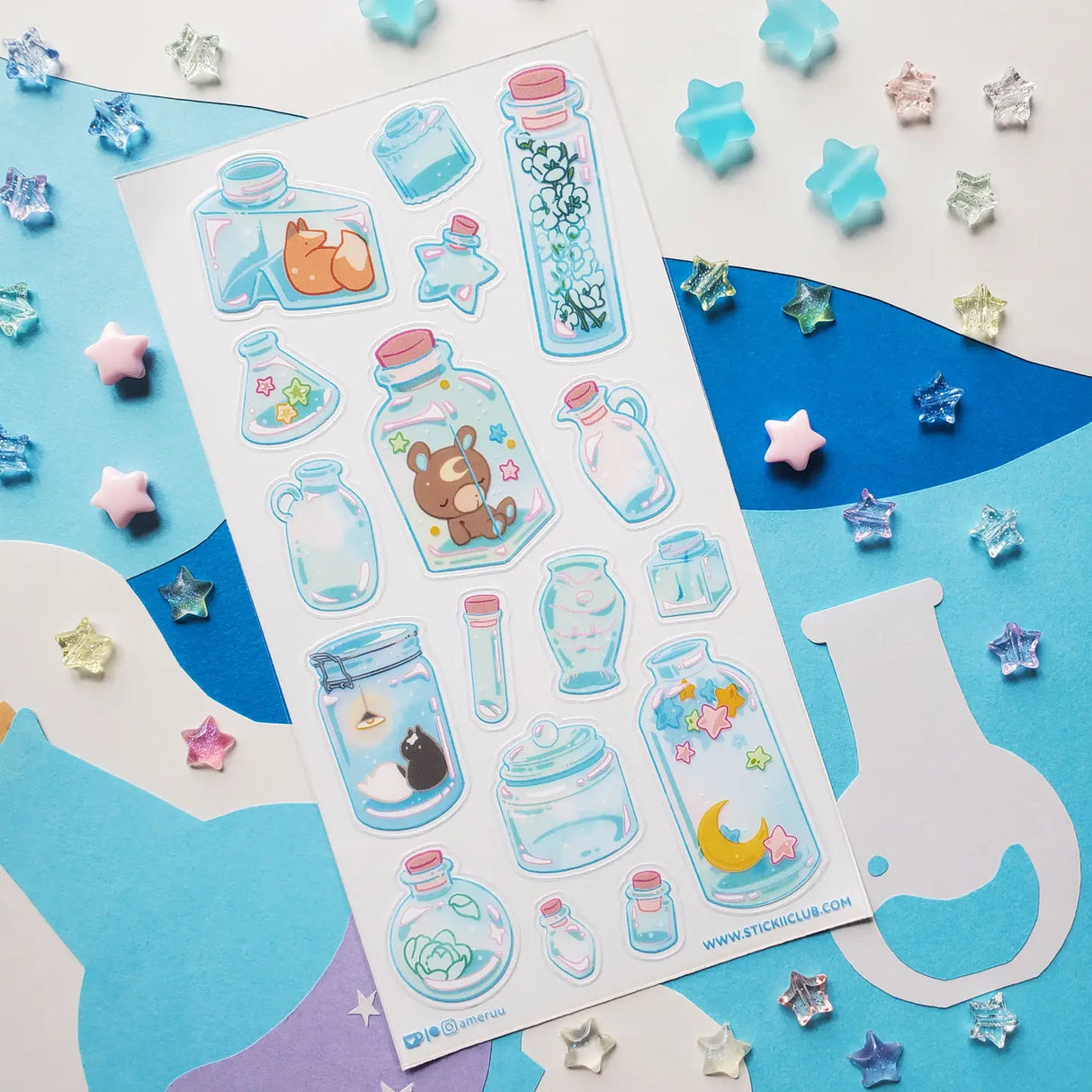 ππ¦ Bottled up and brimming with magic, @ameruu transforms tiny jars into whole little worlds you can hold in your hands. Sleepy foxes and bears curl up for a nap, twinkling stars sparkle beside crescent moons, and delicate blooms and tiny treasures are tucked safely behind glass. From star-shaped vials to oversized bottles holding fragments of the night sky itself, this sheet is a pocket-sized universe, ready to sprinkle some stardust onto your favorite spreads.
Art by: @ameruu