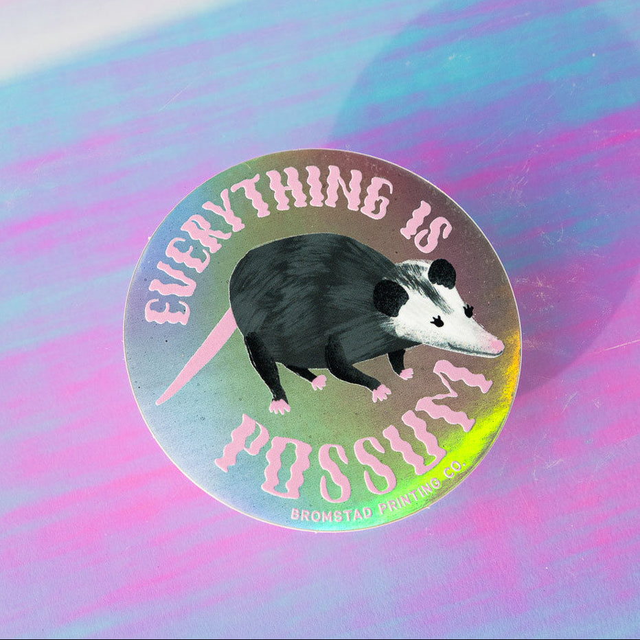 For the person who loves Tegan and Sara AND possums! Everything is awesome with this trippy holographic sticker featuring a charming possum illustration and the words "Everything is Possum." This 3" holograph sticker is ideal for adorning water bottles, laptops, and more.