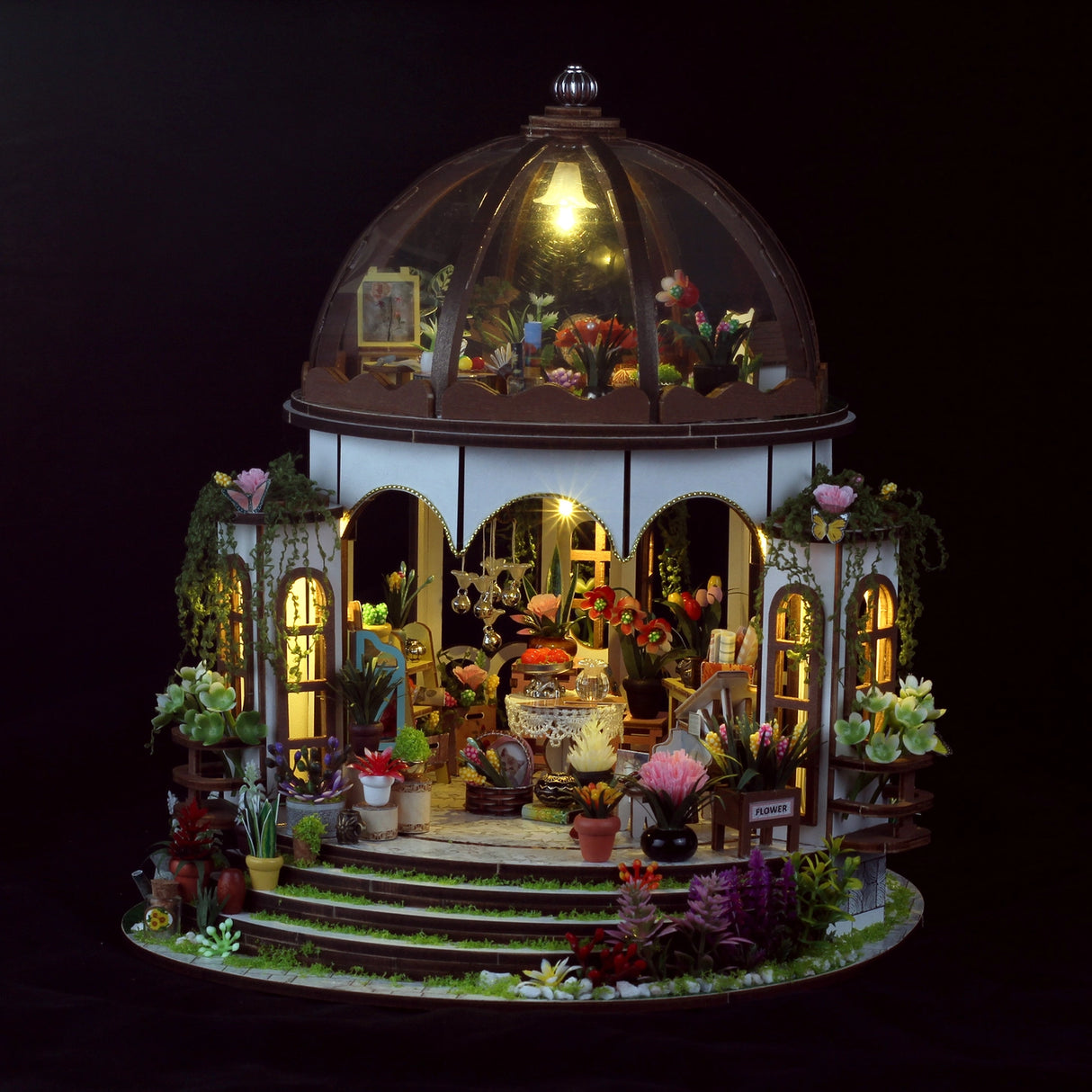 Step into a tranquil garden escape with this miniature kit-a sun-drenched sanctuary filled with flourishing plants, rustic charm, and peaceful vibes. This beautifully crafted greenhouse-style gazebo features delicate woodwork, glass-like panels, and an inviting open-air design surrounded by vibrant flowers, climbing vines, and cozy garden furniture. Whether you're dreaming of a relaxing afternoon under the sun or a quiet place to sip tea and tend to your plants, this miniature brings that dream to life-one