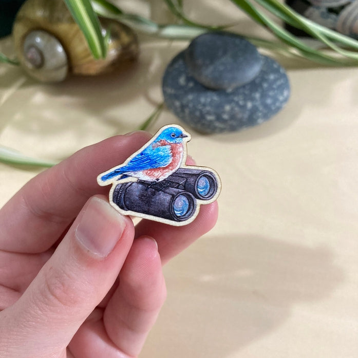 Pájaro azul oriental con binoculares en un alfiler de madera