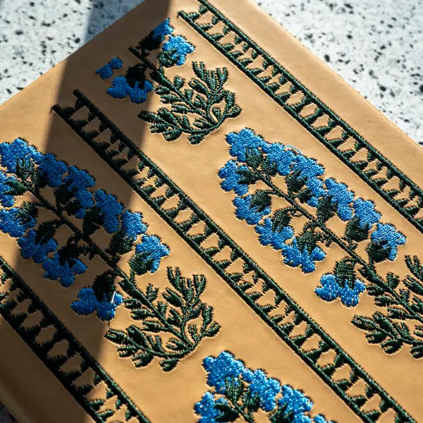 Embroidered Delphinium Flower Hardbound Notebook
A premium hardcover notebook featuring precision embroidery on a vegan leather cover. Designed for everyday use, it includes smooth-lined pages, a Smythe-sewn layflat binding for effortless writing, and a satin ribbon to mark your place.
New inside page design
Soft Touch Hardcover
5.75" x 8.25"
144 Lined Pages
Contrast Endpages
Satin Ribbon Bookmark & Pen Loop