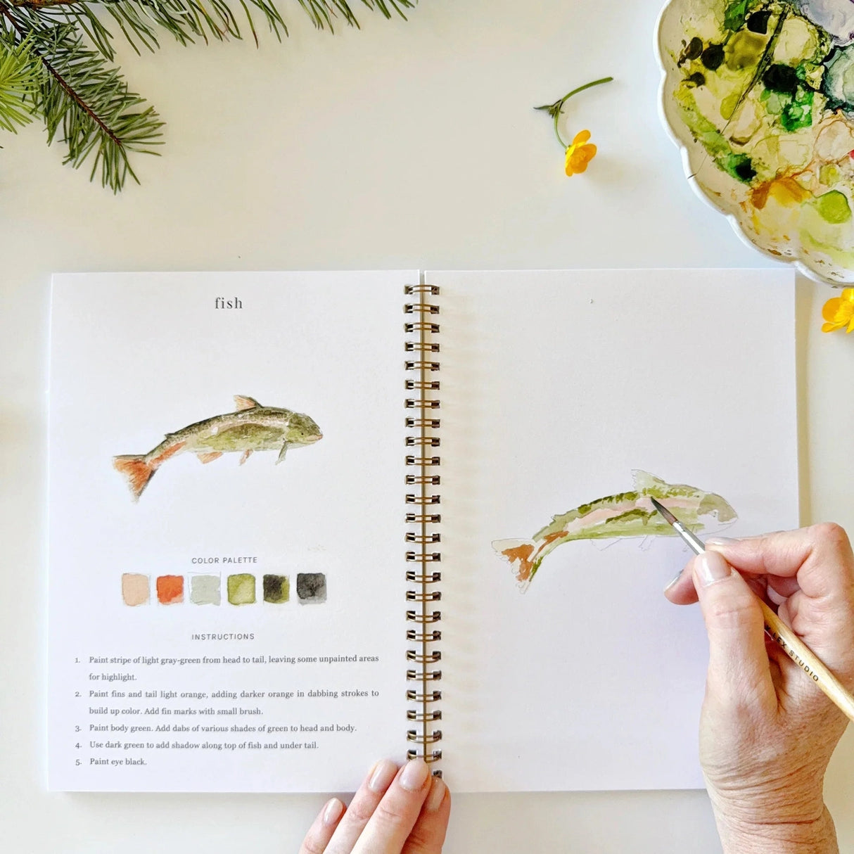 Twelve camping illustrations — a vintage camper, lantern, campfire, tent, canoe, s'mores, and more — each pre-outlined with step-by-step instructions. Paintings take about thirty minutes from start to finish, making it approachable for first-time painters and a favorite for gifting.