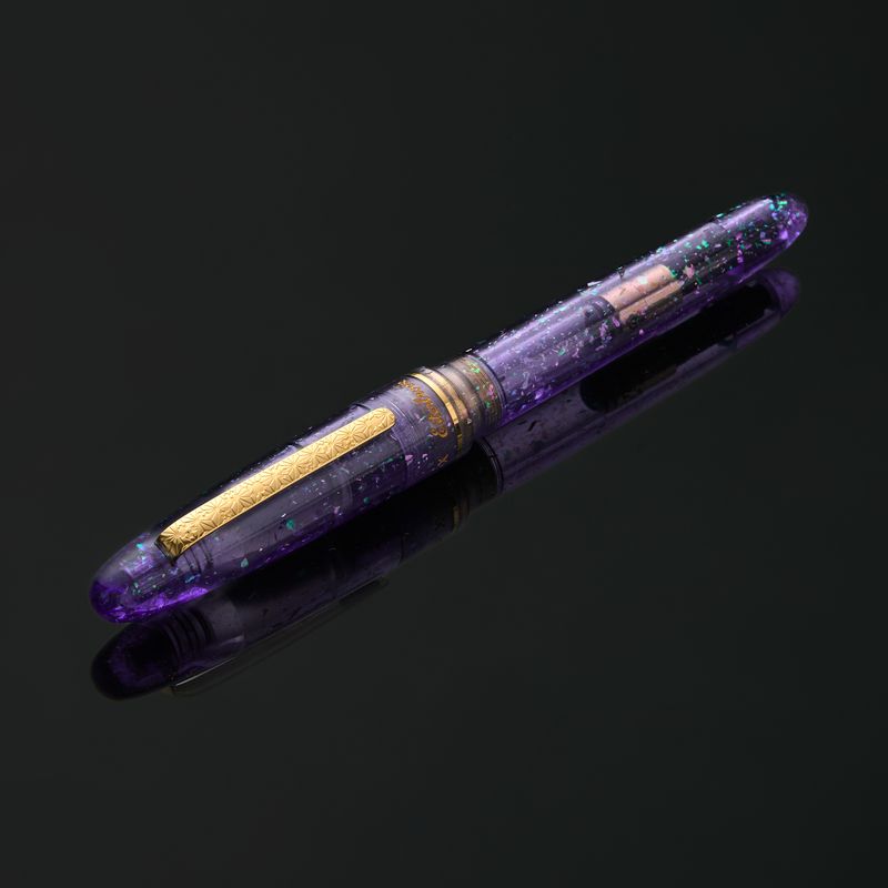Esterbrook x Sakuradragon Sakura Street Estie Fountain Pen
Created with artist Cindy Duong of Sakuradragon, the Sakura Street Estie brings her imaginative illustrated world to Esterbrook's traditional Estie fountain pen. Its U.S.-blended material combines translucent purple with colorful glitter sparkle, while the custom clip is etched with Cindy's Sakura pattern. Dual Esterbrook and Sakuradragon engraving and a gold-plated converter finish the design. Each pen arrives in special packaging with Japanese gi