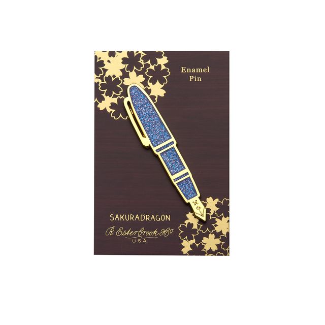 Carry the Sakura Street Estie beyond the page with this oversized hard enamel lapel pin. The 7.5 cm gold- plated design recreates the fountain pen with a sparkle effect inspired by its translucent purple material. It brings one of the collaboration's central designs to jackets, bags, and pin collections.