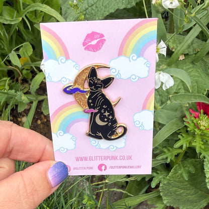 Cute, cuddly and clever – there’s no cat quite like a Sphynx! This fab enamel pin features a black Sphynx covered in mystical symbols, sitting in front of a crescent moon with 2 purple clouds.
The pin is 42mm (1.65”) tall, and is made from gunmetal hard enamel, with glitter and UV printed details. It's secured with 2 pink clutches to keep the pin in place.