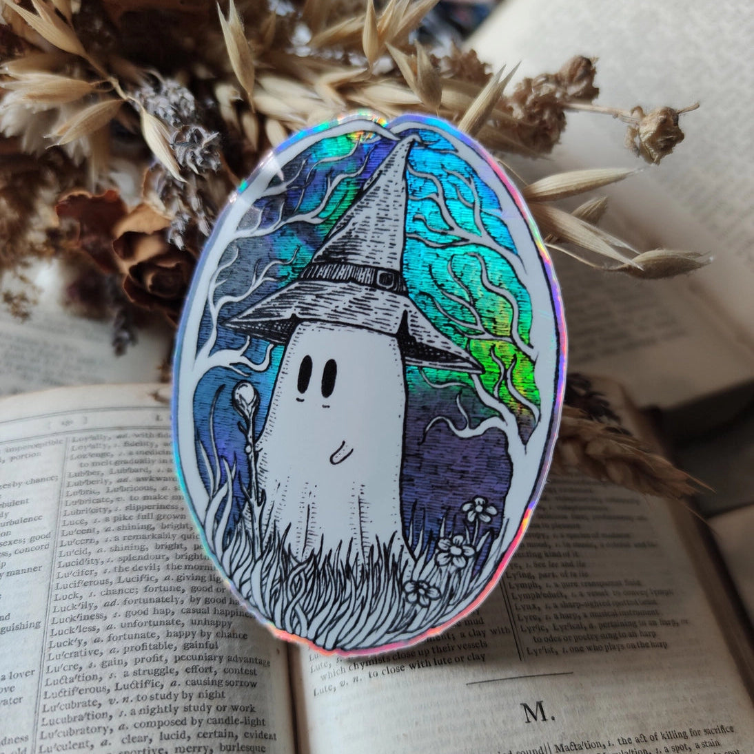 A magical ghostie on a shiny cosmic sticker, from my original artwork.
Die-cut vinyl holographic sticker, suitable for interior or exterior use; perfect for a phone, laptop, car, planner, or wherever you want to put a shiny robot. Measures approximately 7.5cm (3 inches) at its widest point. Difficult to photograph, but it shimmers beautifully under the light with an exciting oilslick rainbow effect.