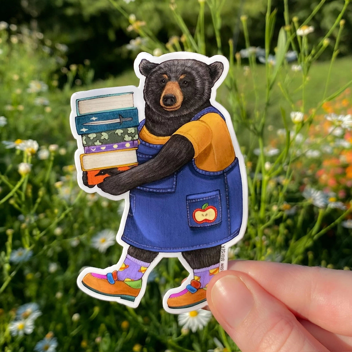 Don't let the colorful footwear, whimsical socks, and adorable apple jumper fool you: although she's normally sweeter than the honey she puts in her tea, this li-bear-ian isn't afraid to show her claws if you try to ban books on her watch!
This die-cut gloss vinyl sticker is durable, weatherproof, and perfect for water bottles, notebooks, laptops, bikes, and all sorts of other surfaces! Make sure to clean and dry the surface thoroughly before applying.