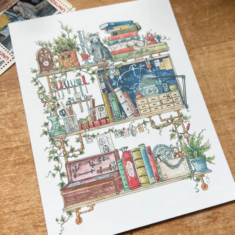 Postcard featuring my original watercolor and ink illustration of the oddities, books, and tools tucked away in the shelves of a vintage inventor, including an assortment of tiny robots, a fire extinguisher, and a raccoon who is definitely not certified to operate the drill press.
