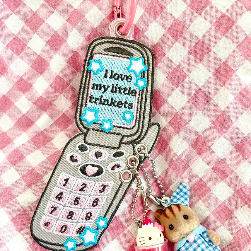 These cute embroidered keychains attach with a colorful ring clasp and are perfect for attaching to your keys or bag to bring with you on all of your adventures!
This particular cell phone design is inspired by Y2K and 2000s. It features extra silver grommets to hang more keychains and showcase your favorite charms! Perfect for any trinket and knick knack hoarder.
Includes one keychain only.
Embroidered on both sides.
Materials: Cotton, Polyester, Brass