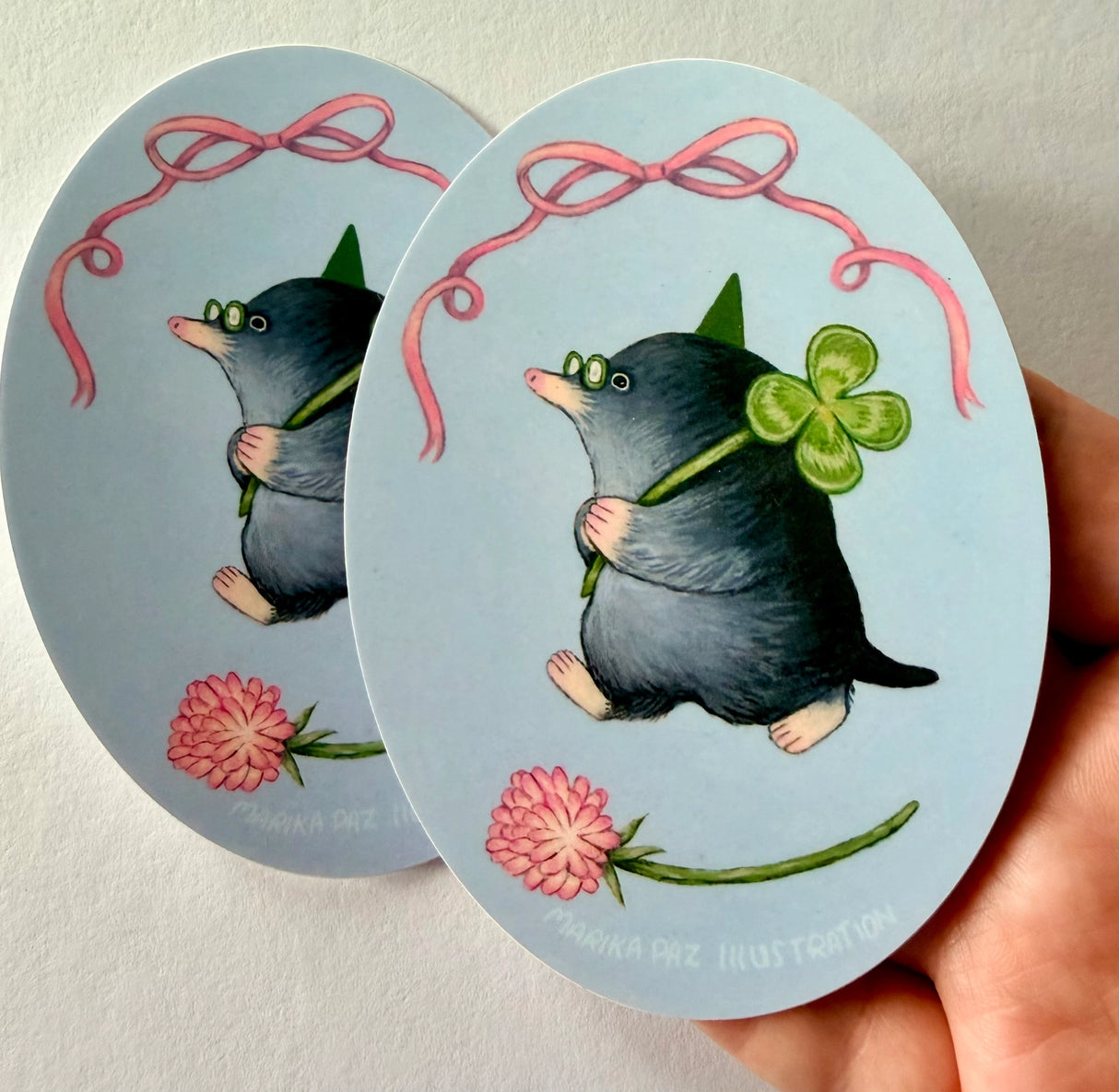 A very lucky mole takes their four-leaf clover home.
This vinyl matte sticker is weather and waterproof-stick it on a notebook, bike, or car- it's going to stick around! Heck, throw it on a water bottle and through the dishwasher. This sticker can go anywhere. Sticker measures 3.25" x 4.5" Printed in USA.