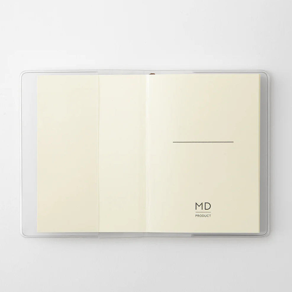 A transparent cover that fits snugly around your MD Notebook
This is a special cover that gently wraps your MD Notebook. The transparent cover protects the notebook from dirt without ruining its appearance.
It subtly protects your notebook from water and dirt without interfering with its characteristics. If you put the cover on with the glassine paper still wrapped around it, the inorganic feel of the vinyl will be softened.
Because it is transparent, you can enjoy the cover design, illustrations, and writ