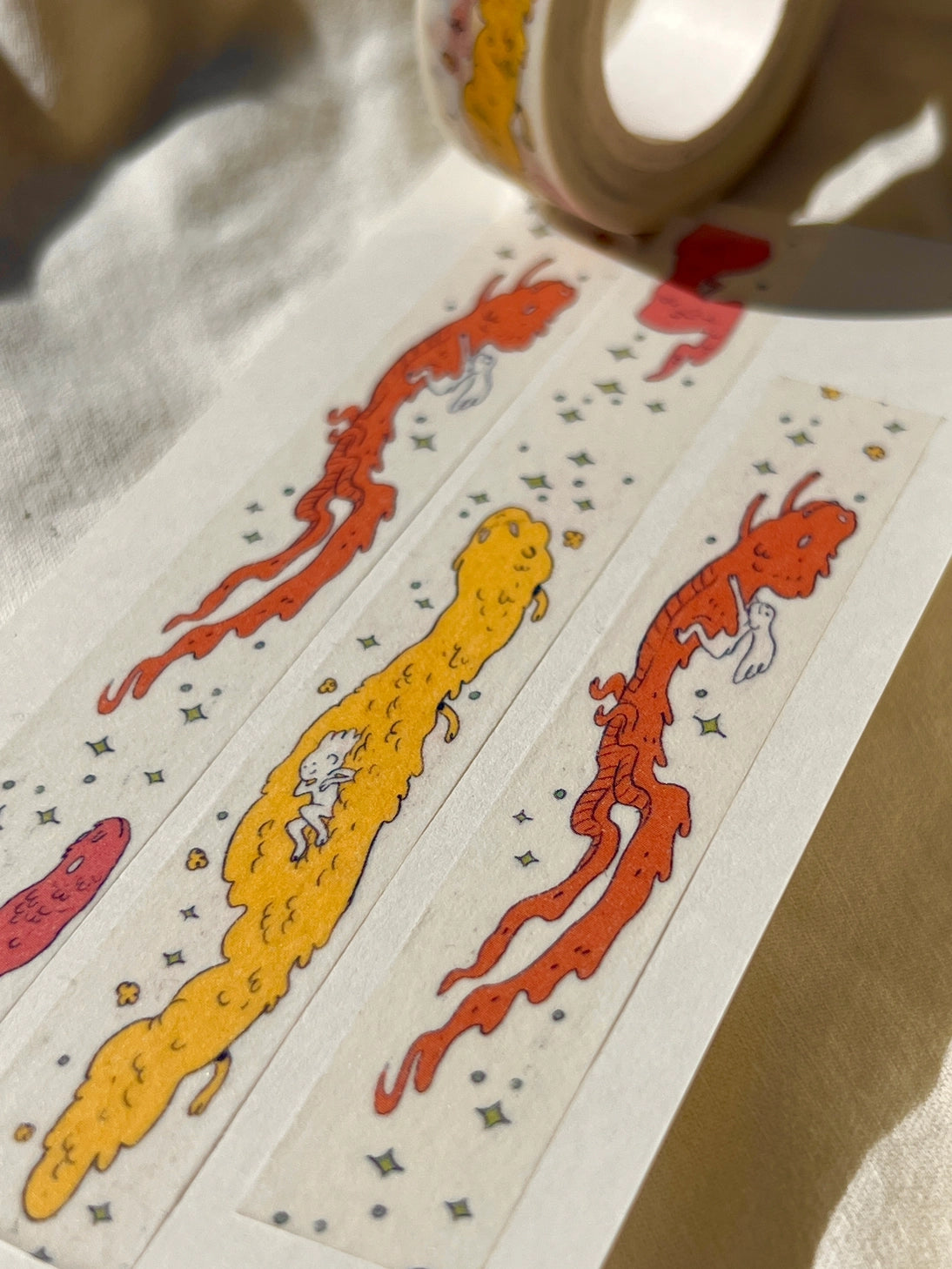 This Dragon washi tape features three soft, fluffy dragons that the dragon rider girl has befriended.
This roll is 15mm wide x 10m of paper tape. Washi tape is super durable and flexible. It tears easily and can be safely applied to a variety of surfaces; it doesn’t leave a sticky residue behind, making it especially ideal for stationery and hanging prints temporarily.