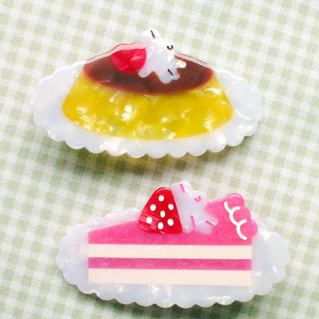 Pudding & Cake Hair Clips as a set of two clips. Clips are 2.5 inches long, made of acetate and have an alligator style clip on the back.
Clips should not be submerged in water.
Hair clips come with a backing card in a plastic sleeve.