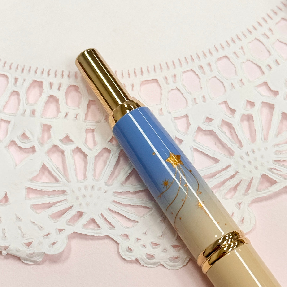 To commemorate 36 years of Kin Chi, this exclusive Pilot Capless “Starry Dawn” captures the quiet magic of the moment when night begins to surrender to morning.
Its softly layered colors move from pale blue through warm golden yellow and into a vivid morning blue, echoing the changing sky just before sunrise. Against the clouds, a radiant golden sun emerges while a scattering of stars still lingers above, an in-between moment where night and day meet.
