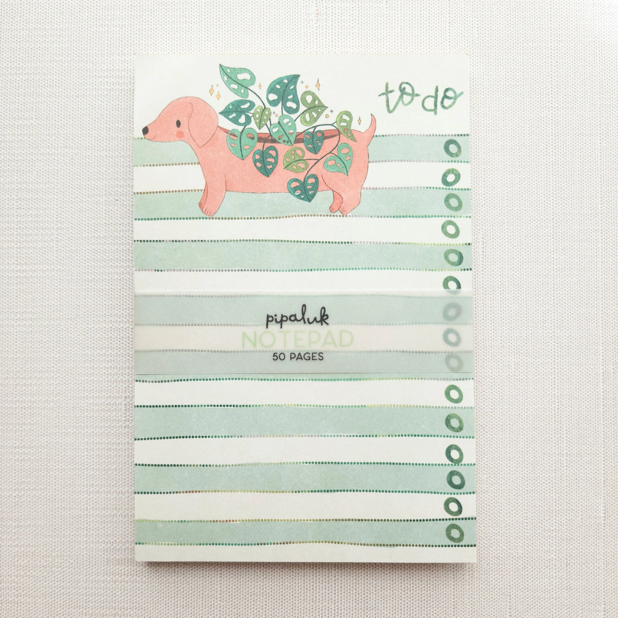 In a sunny Wildflower Woods cottage, a dachshund planter rests near a stack of well-loved books, leafy greens spilling gently from its back. This notepad brings that cozy, decorative moment to your desk, making everyday lists feel a little more inviting.
Designed to be practical without feeling busy, this notepad offers a simple, cheerful way to keep track of daily to-do lists and planning.