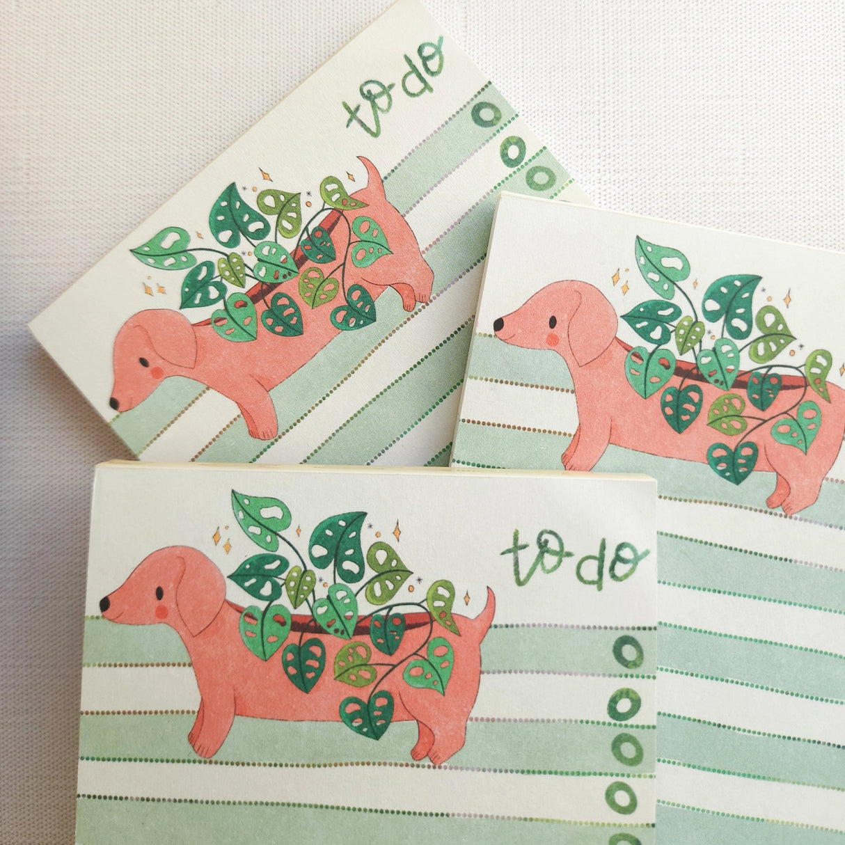 In a sunny Wildflower Woods cottage, a dachshund planter rests near a stack of well-loved books, leafy greens spilling gently from its back. This notepad brings that cozy, decorative moment to your desk, making everyday lists feel a little more inviting.
Designed to be practical without feeling busy, this notepad offers a simple, cheerful way to keep track of daily to-do lists and planning.