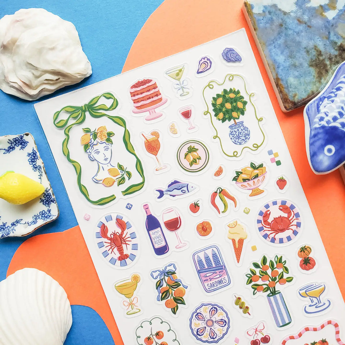🍋🦞 Ciao to sunny days, seaside snacks, and a table full of color! This playful sheet is packed with lemons, tomatoes, seafood, spritzes, sardines, patterned tiles, and plenty of Mediterranean flair. Add in a few artsy portraits and bright floral details, and it’s basically a whole summer getaway squeezed onto one sticker sheet.
Top Coating: None
Adhesive Layer: PVC (plastic)
Backing Layer: Clear
6.69" x 3.54".
Weight - 0.03lbs
1 sheet included