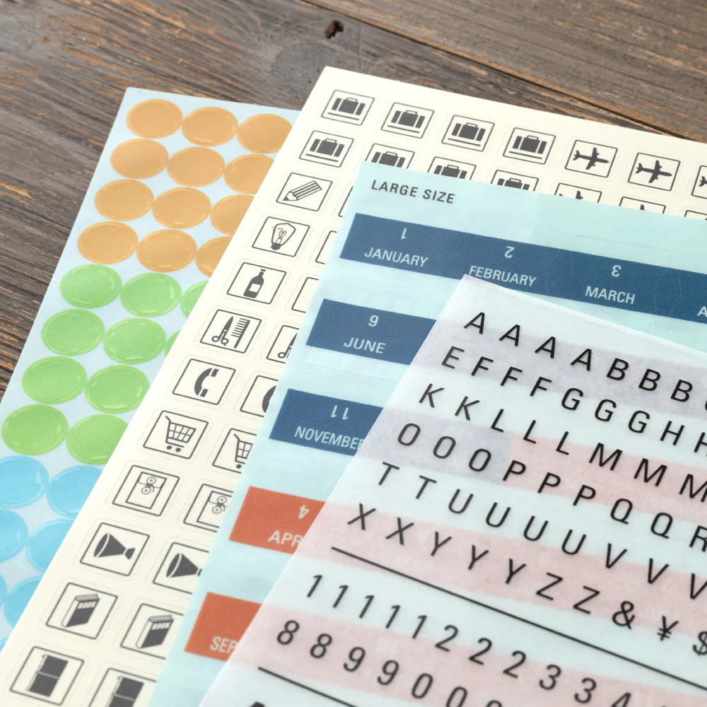This is a sticker set for customizing TRAVELER’S notebook that makes it more fun, including index and pocket stickers, icon stickers to represent different plans, dry transfer, and stickers to decorate the cover. The 2026 version features a design with a theme of “TRAVELER'S SPIRIT"
You can customize the cover of the 2026 diary or other notebooks with stickers of analog motifs. Have a good trip with THE TRAVELER'S SPIRIT in 2026.