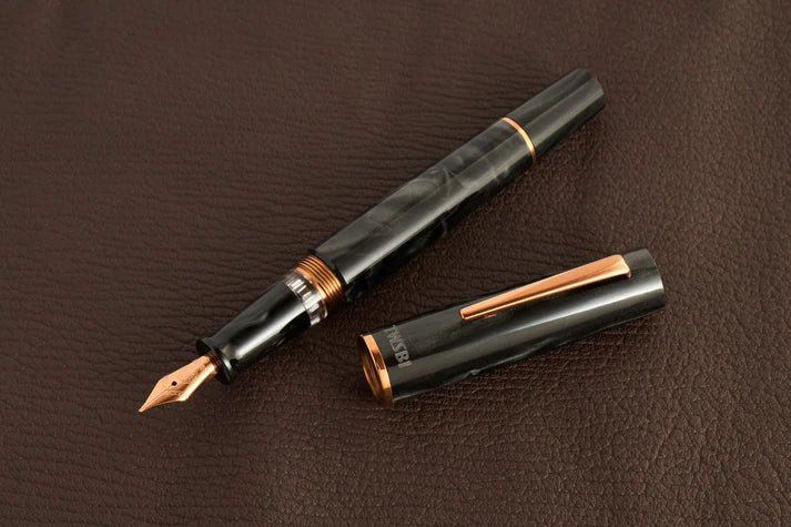 This TWSBI Obsidian fountain pen is made of a dark grey/black swirled acrylic resin, inspired by the natural obsidian stone. The pen is complemented by rose gold-plated trim and is equipped with a rose gold-plated stainless-steel nib.
Pen cap is able to post onto the back of the pen
Piston Filler Fountain pen.
Simply unscrew the end cap, dip into ink, screw back the end cap, and you're done! Ready to write!!