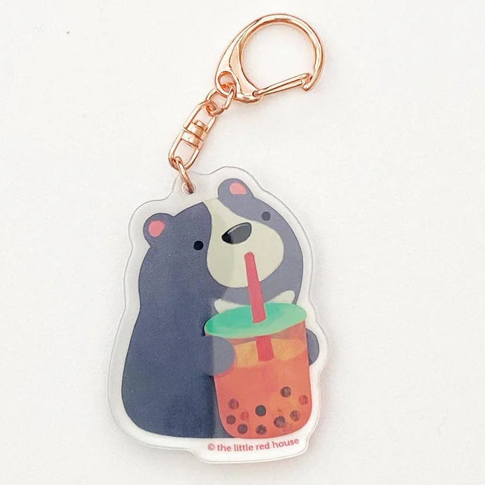 This adorable keychain features a grey and white moon bear sipping a boba milk tea or bubble tea. Includes a rose gold colored metal swivel clasp. Packaged with protective film on both side. All keychains are packaged with illustrated backing card and clear cello bag.
Designed and Illustrated by Aggie Cheung for The Little Red House
Dimension: 1.5 x 2 inches
