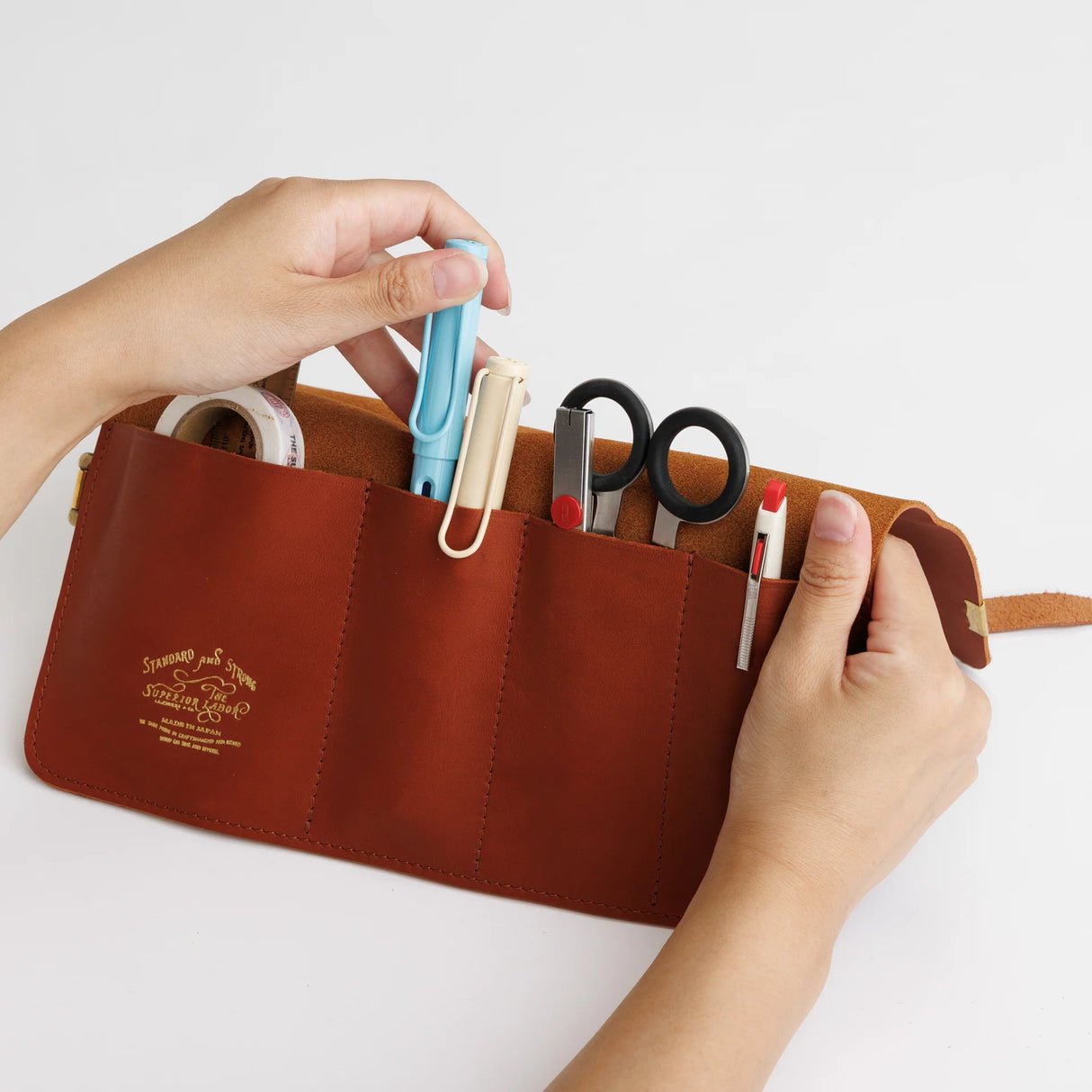 The SUPERIOR LABOR Glove Leather - Roll Pen Case
The discontinued pen roll has returned with a refined new design. A brass tag accents its raw-cut edge, while the logo inside is finished with elegant gold foil. The result is a fresh look that feels both light and sophisticated.
Pockets in varying sizes hold pens of different types, and when you’re done, simply roll it up and take it with you.
A pen case that combines the joy of displaying your favorite pens with the practicality of ca