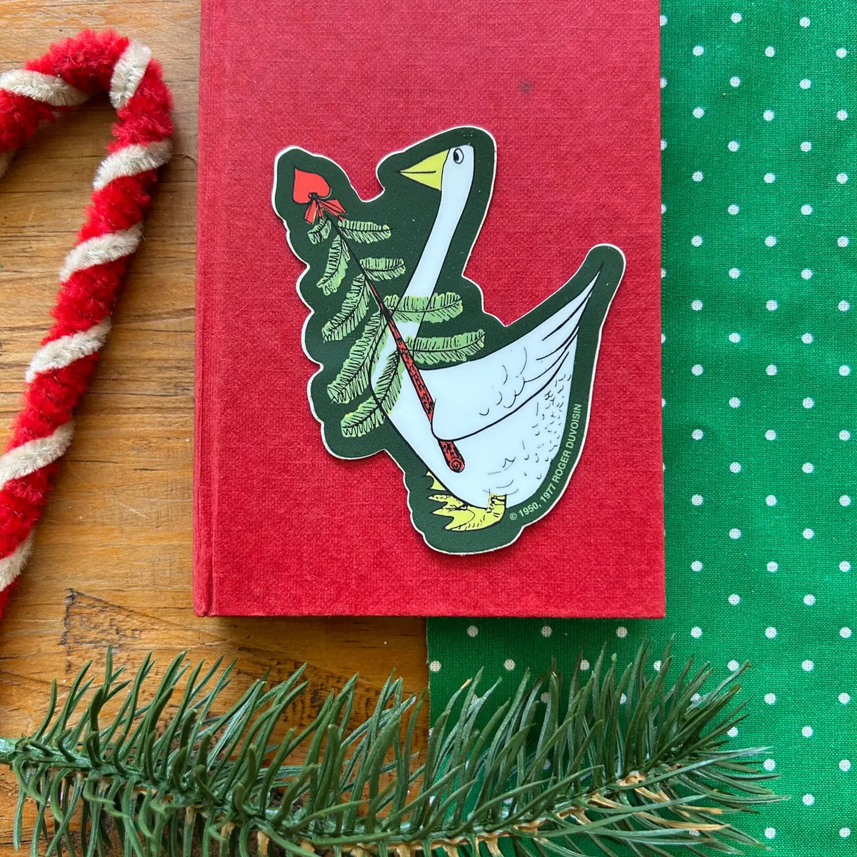 This vinyl sticker features a Petunia® Christmas motif in green tones, proudly made in the U.S.A. from Three Potato Four. Easy to apply to surfaces, it adds a decorative, retro-style touch to gifts and items.