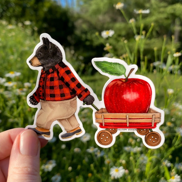 This flannel-clad American black bear is hauling a larger-than-life juicy red apple in his button-wheeled applecart. His family is no doubt polishing off some apple cider donuts while he does all of the hard work. Here's hoping they saved one for him!&nbsp;

This die-cut gloss vinyl sticker is durable, weatherproof, and perfect for water bottles, notebooks, laptops, bikes, and all sorts of other surfaces!

Make sure to clean and dry the surface thoroughly before applying. 