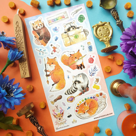  @yuhuirustudio’s woodland artists have traded the forest floor for a table full of paints, brushes, wax seals, and colorful little treasures! A fox holds its favorite brush, a red panda chooses the perfect shade, and one sleepy helper has decided a watercolor palette makes an excellent place for a nap.

Art by: @yuhuirustudio


One sticker sheet is included.
Top Coating: None
Adhesive Layer: Paper
Backing Layer: Paper
Size: 6.69"x3.54"
Weight-0.03oz