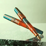 BENU presents the newest Haute Collection — a line of elegant, fashion-inspired pens that blend classic charm with bold, modern flair. The designs include both subtle and vibrant styles, showcasing BENU’s signature glitter and color artistry. Each pen features a faceted body with alternating wide and slender facets, complemented by either gold-plated or chrome-plated trims for a sleek, timeless look.

With a bold orange and teal body streaked with gold, Chic turns heads with runway-ready style. Fashion-forw
