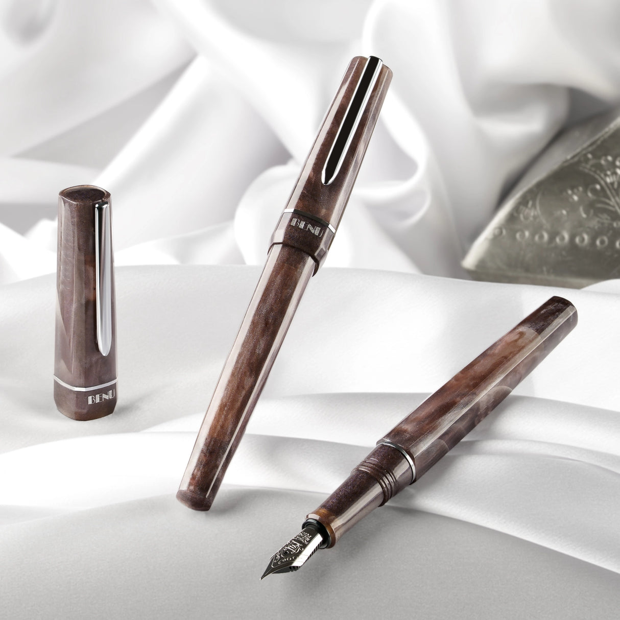 BENU presents the newest Haute Collection — a line of elegant, fashion-inspired pens that blend classic charm with bold, modern flair. The designs include both subtle and vibrant styles, showcasing BENU’s signature glitter and color artistry. Each pen features a faceted body with alternating wide and slender facets, complemented by either gold-plated or chrome-plated trims for a sleek, timeless look.

With smoky gray marbling and polished chrome hardware, Satin is the essence of modern elegance. Understated