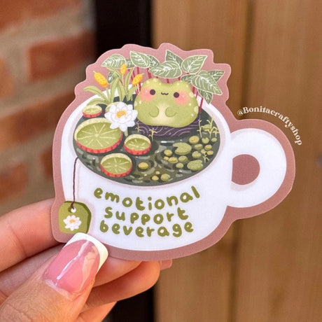 Bring some cozy comfort to your day with this “Emotional Support Beverage” frog sticker! Featuring a cute frog relaxing in a teacup pond surrounded by lily pads and flowers, this sticker is perfect for frog lovers, tea enthusiasts, and anyone who needs a little emotional support beverage energy.

♡ STICKER DETAILS ♡
~ Sticker size: 2.7’’ inches
~ Printed on matte sticker paper
~ Matte Laminate finish ✨
~ Scratch-resistant surface, water-resistant
~ ONLY Handwash. This sticker is not dishwasher or microwave 