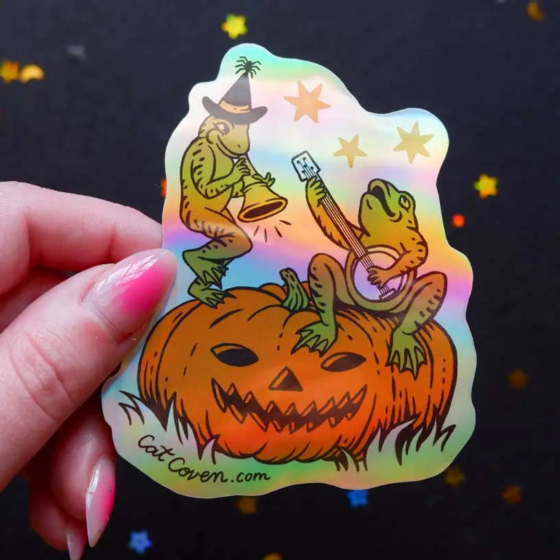 Cat Coven -&nbsp;Halloween Frogs Holographic Vinyl Sticker

Celebrate your love for Halloween with this cute new Halloween frogs vinyl sticker! This sticker is perfect for your journal, water bottle, laptop, and more.

Waterproof, UV protected &amp; high temperature resistant
3 x 3.7 inches and holographic!
Colors may vary slightly from your computer screen to real life product