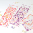 The Cocoroll Sweets deco sticker sheet features Cocoroll surrounded by adorable candies. Available in pink and purple versions, these cute deco stickers are the perfect addition to any polaroids/toploaders, journals, and more. The sparkly holo overlay adds an extra touch of shine and magic.

Dimensions: 2.7” x 8" (6.8cm x 20.5cm)
Quantity: 1 sheet