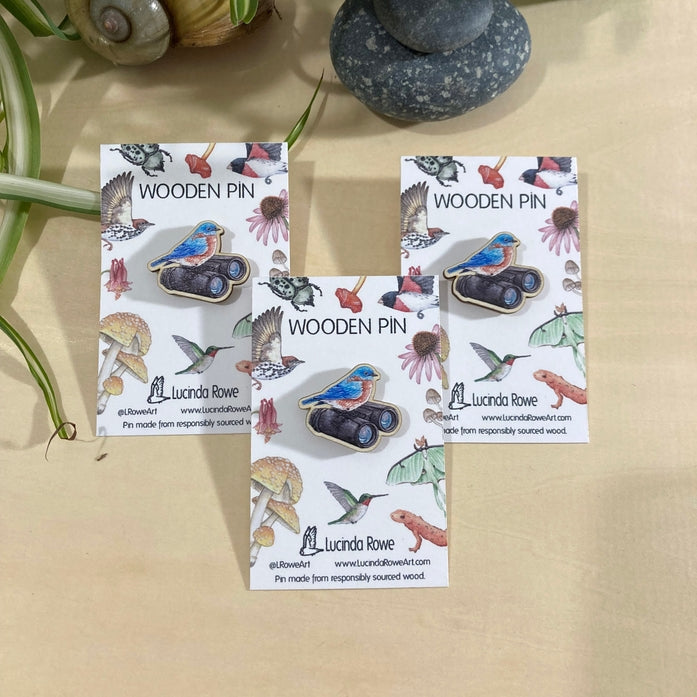 Pájaro azul oriental con binoculares en un alfiler de madera 