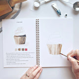 Emily Lex Studio Watercolor Workbook - Baking

Twelve baking illustrations — a cupcake, layer cake, mixing bowl, lattice pie, tray of cookies, rolling pin with cookie cutters, and more — each pre-outlined with step-by-step instructions. Paintings take about thirty minutes from start to finish, making it approachable for first-time painters and a favorite for gifting.

12 beginner-friendly illustrations
Thick 120lb watercolor paper&nbsp;
Lay-flat pages with spiral binding for hassle-free painting and easy te