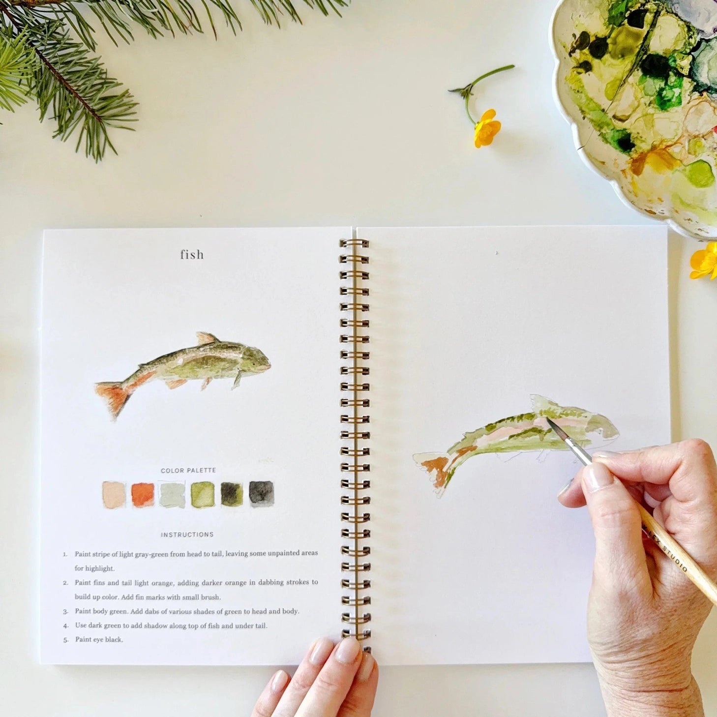 Twelve camping illustrations — a vintage camper, lantern, campfire, tent, canoe, s'mores, and more — each pre-outlined with step-by-step instructions. Paintings take about thirty minutes from start to finish, making it approachable for first-time painters and a favorite for gifting.