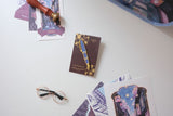 Carry the Sakura Street Estie beyond the page with this oversized hard enamel lapel pin. The 7.5 cm gold- plated design recreates the fountain pen with a sparkle effect inspired by its translucent purple material. It brings one of the collaboration's central designs to jackets, bags, and pin collections.