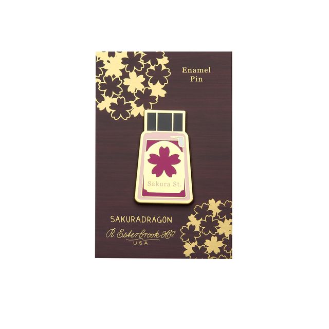 The Sakura Street Ink Lapel Pin turns one of the collection's coordinating ink bottles into a collectible hard enamel design. Measuring 4.5 cm and finished with gold-plated details, the pin carries the colors and imagination of Cindy Duong's Sakura Street artwork onto a jacket, bag, or display board.