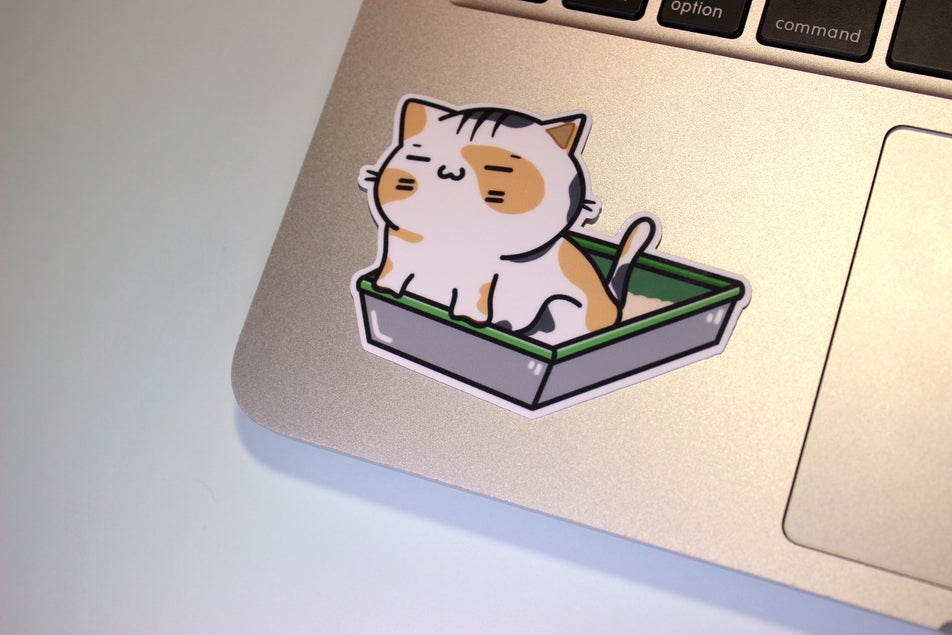Pegatina de vinilo con un gato divertido en una caja de arena