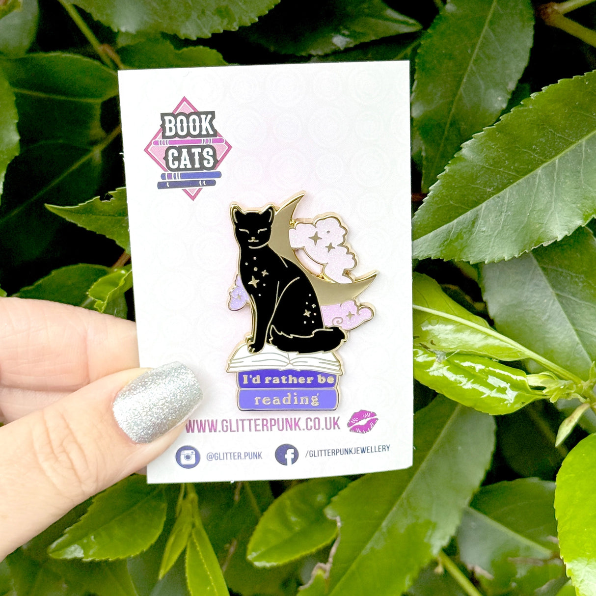 We’ve all sometimes wished we were at home with a hood book, rather than having to deal with the real world! This super cute pin features a black cat sitting on pink &amp; purple books with the slogan ‘I’d rather be reading’. Behind the cat is a large crescent moon and a pair of glittery pastel clouds.

Measurements: 45mm (1.77”)