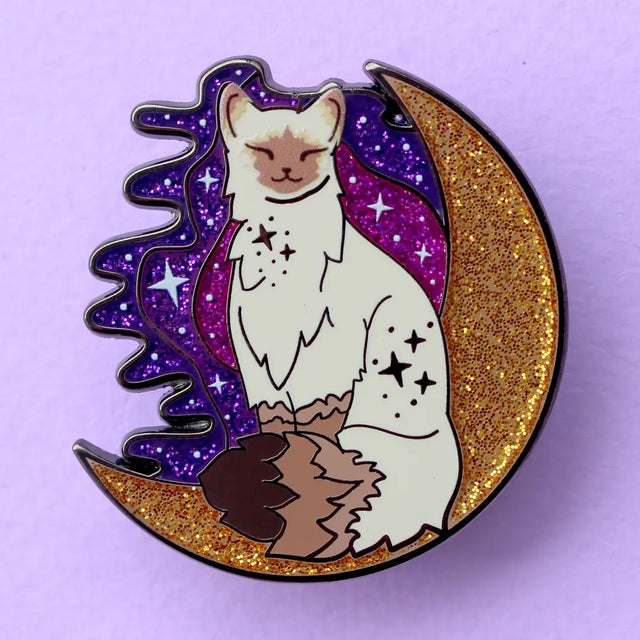 Calling all owners of a long haired pointed / meezer cats! This super cute design features the cat sitting in front of a sparkly moon with a glittery, starry sky in the background.

The pin is 40mm (1.57”) tall, and is made from gunmetal hard enamel, with glitter and UV printed details. It's secured with 2 pink clutches to keep the pin in place.