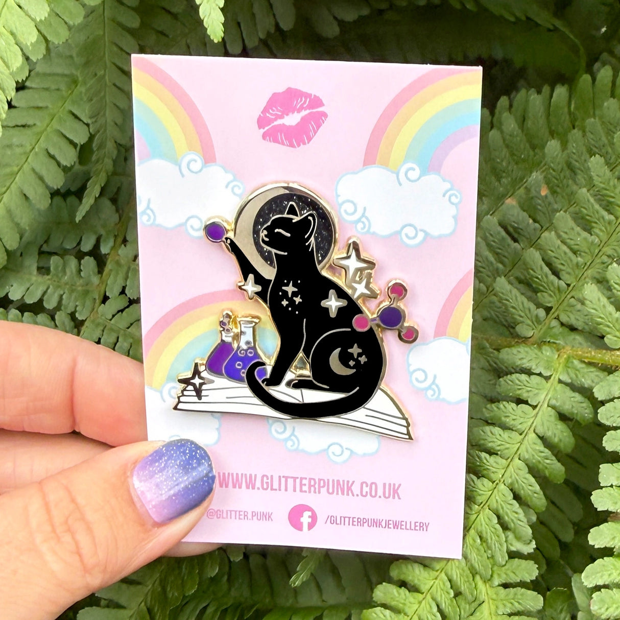 If you’re passionate about science and partial to cats, this awesome pin is perfect for you! It features a black cat sitting on a book and playing with atom parts. It also features a glittery moon and two beakers filled with purple liquid.

The pin is 42mm (1.65”) tall, and is made from gunmetal hard enamel, with glitter and UV printed details. It's secured with 2 pink clutches to keep the pin in place.