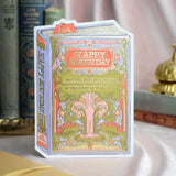 A bookish birthday card for lovers of stories and symbolism. This periwinkle card features a lush, gold-foiled tree with an open book at its roots and the message “May this year be another beautifully written chapter in the story of your life.” A thoughtful and elegant foil-pressed stationery piece.

Product Details:
- Dimensions: 5" x 7"
- Die-cut antique book-style design
- Hand-illustrated with gold foil details
- Blank interior
- Offset and foil printed
- Comes with envelope