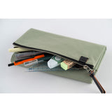 Its standout feature is the generously sized pocket, but its overall appearance remains clean and minimal. With its calming and gentle oakmoss color, the design is versatile and suits anyone. Though it folds into thirds and fastens with a magnetic closure, the cover is light in hand. The aim was effortless elegance, something that looks sharp without being flashy. The material is a soft nylon with a sophisticated sheen.