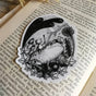 Sticker featuring a little robot and his faithful frog companion making their way through the haunted graveyard, from original pen and ink artwork by Jon Turner.