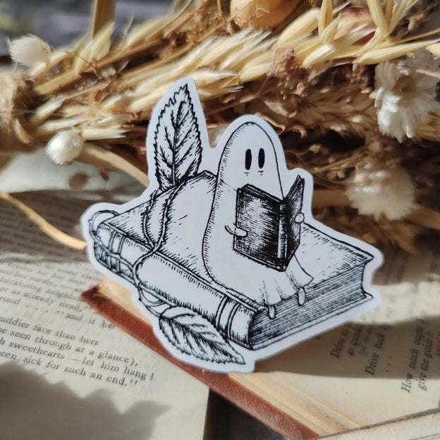 A studious little ghostie catching up on a bit of reading, on a lovely die-cut vinyl sticker, from an original ink illustration by Jon Turner.